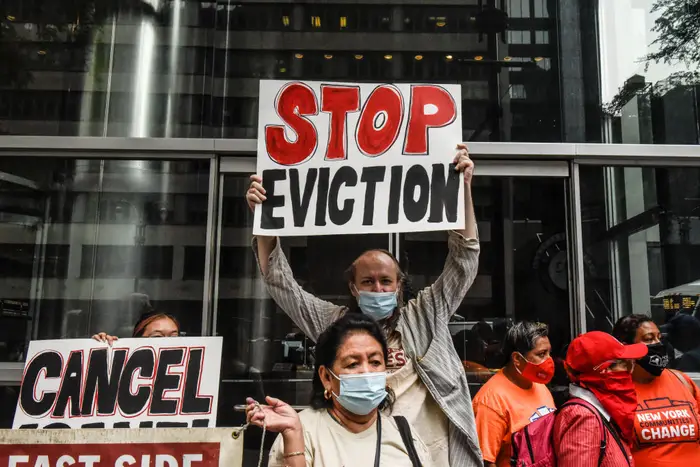A man wearing a blue mask holds a sign that says "Stop eviction"